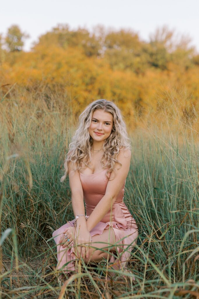 High school senior girl smiling in a golden field at sunset during her portrait session in Malibu field