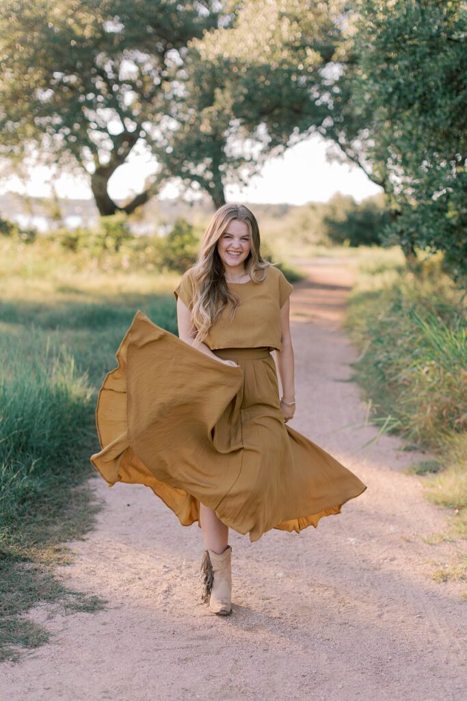 Candid senior portraits of girl in flowy dress during golden hour at a park