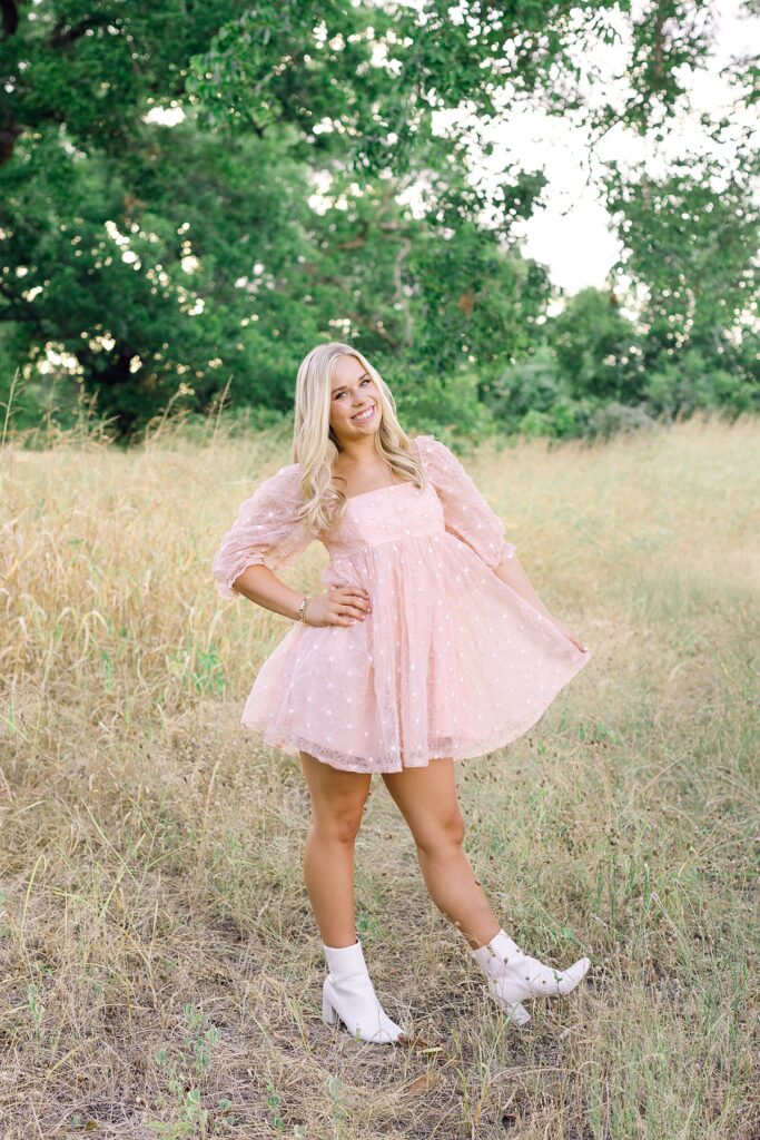 Photo of senior girl in blush pink dress and boots in Southern California field at golden hour
