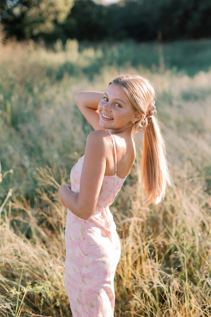 Senior girl in pink maxi dress poses confidently in golden light during a Southern California senior session