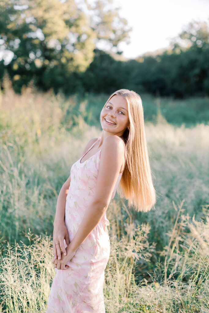 Close-up senior photo of a girl smiling in a golden Southern California field at sunset