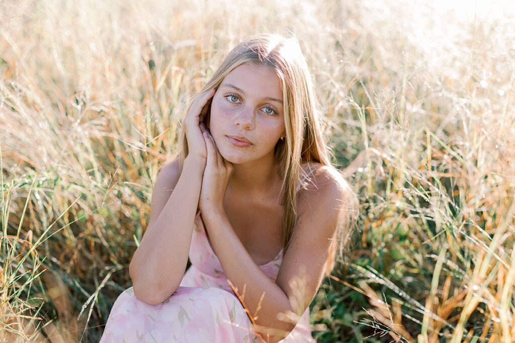 Close-up outdoor senior photo idea in Malibu featuring natural light and soft tones sitting in a golden field.