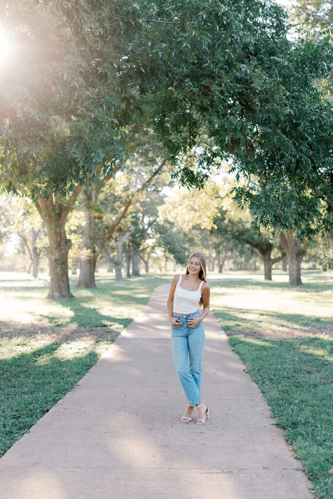 Senior picture idea on a tree-lined pathway in Southern California with golden sunlight in Malibu.