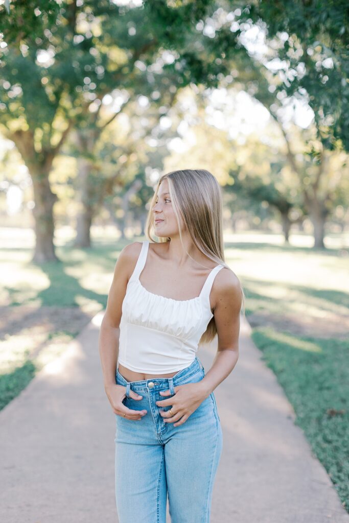 Outdoor senior portrait in Malibu wearing jeans and a white top under soft Southern California sunlight.