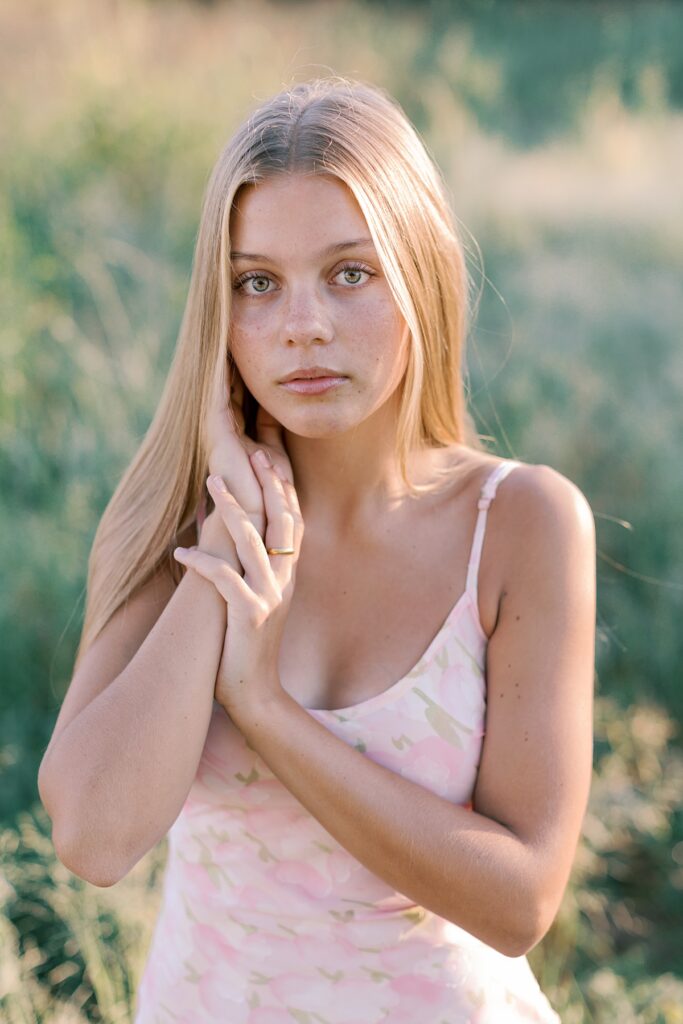 High school senior with long blonde hair poses in soft light for Malibu senior photos in a field