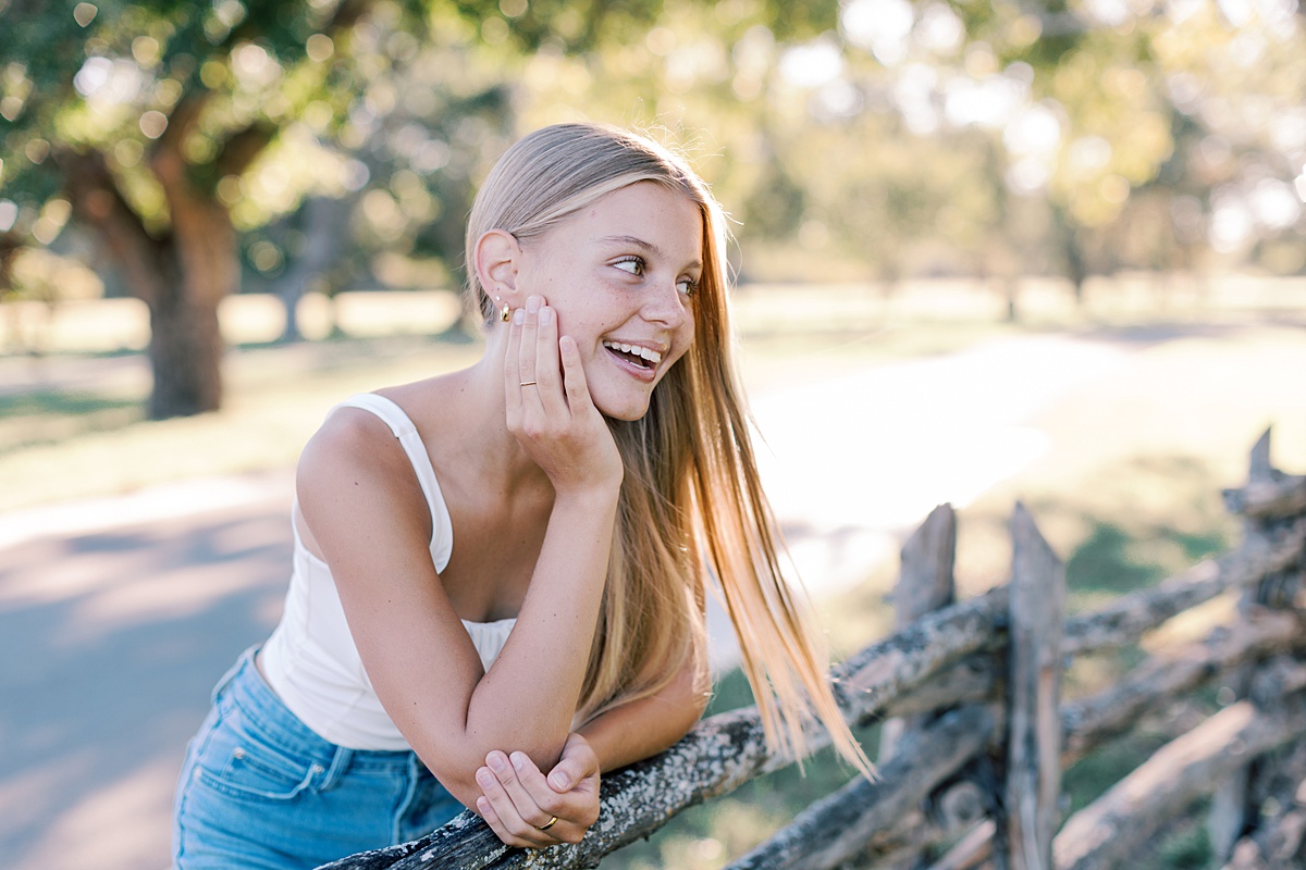 Outdoor senior picture of girl leaning on a wooden fence in Malibu, Southern California during golden hour.
