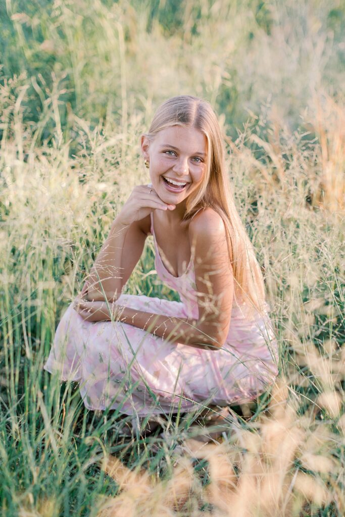 Smiling high school senior in a pink dress posing in golden hour light for her Malibu senior session