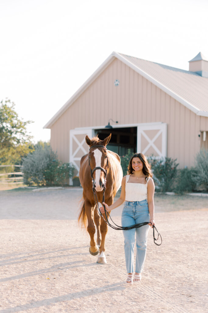 Sunset equestrian senior portrait of girl walking with her horse in golden light.