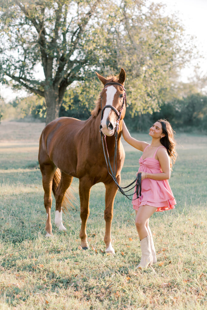 Senior girl in cowgirl boots next to horse – country-western equestrian senior portrait.
