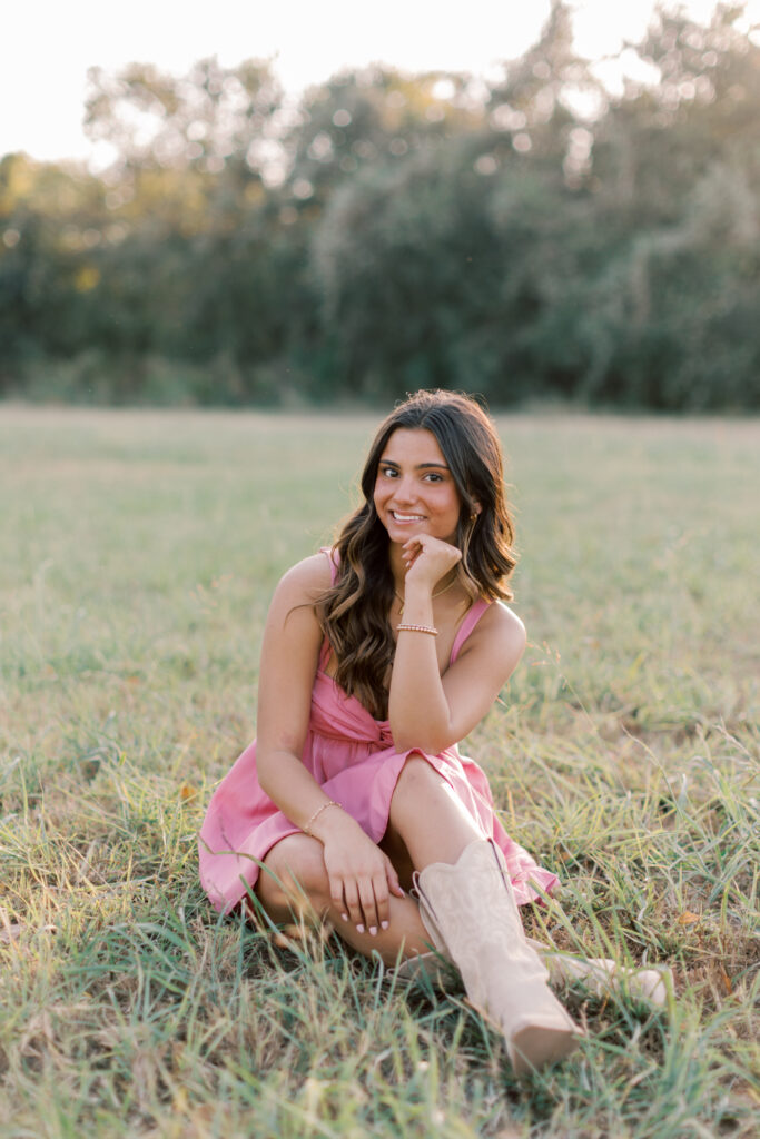 A grounded, soft portrait of Malibu senior smiling while seated in the grass.