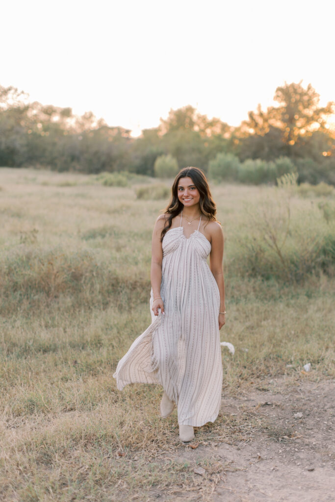 Senior photo walking in open field at sunset, peaceful and serene.