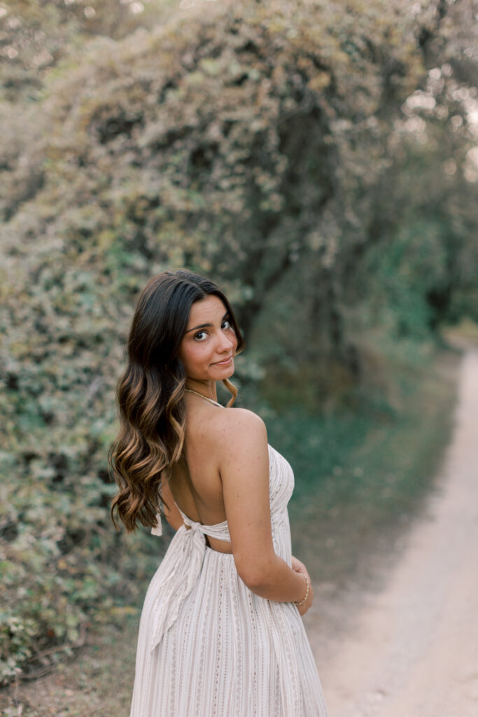 Close up senior portrait of girl softly smiling at camera in soft golden hour light