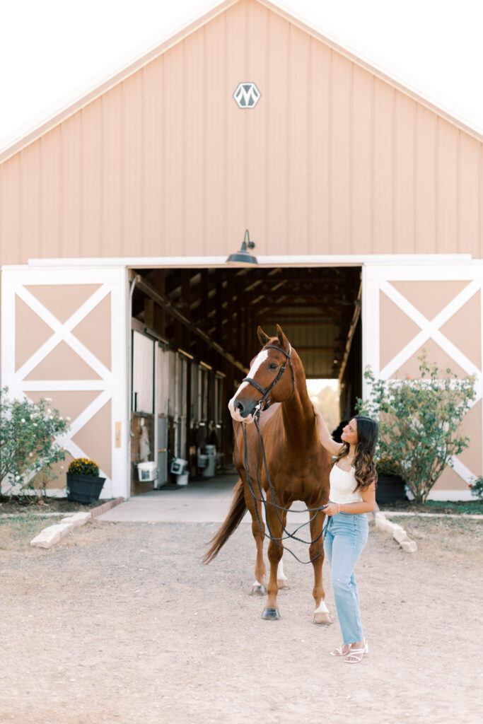 High school senior gently holding reins beside her horse – relaxed and confident equestrian portrait.