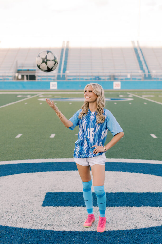 Blonde senior girl tossing soccer ball on football field, Southern California senior photographer