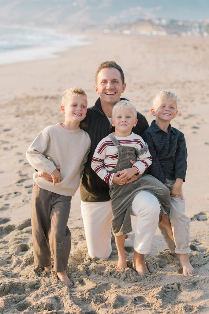Dad smiling with kids on beach by Malibu family photographer