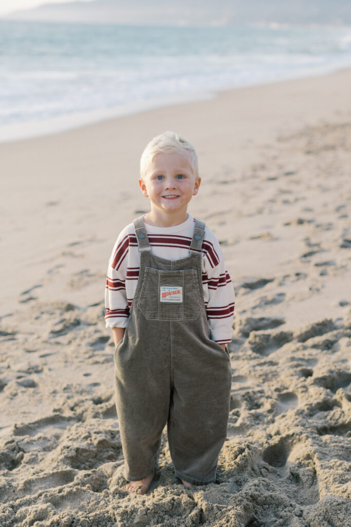 oung child smiling in soft golden light during a Malibu family photoshoot.