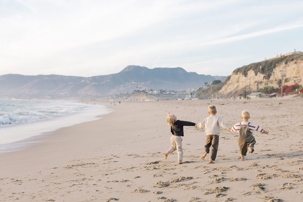 Kids running along the shoreline during golden hour at Westward Beach in Malibu.