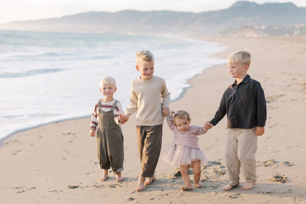 Malibu family photo of kids holding hands smiling at Westward beach.