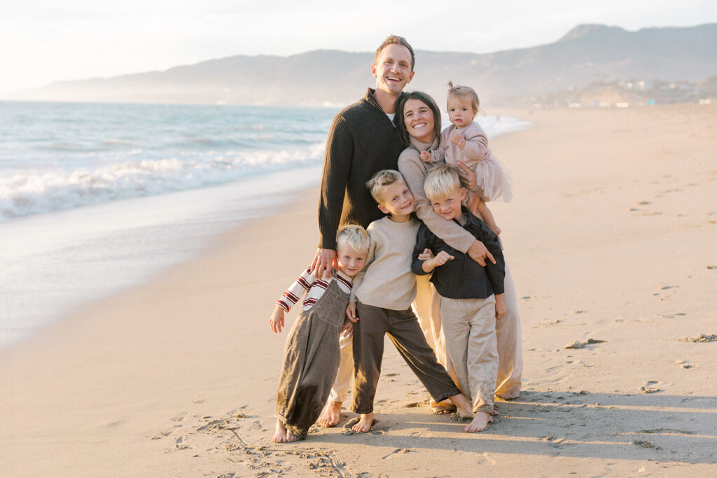 Family laughing together on the sand during a warm sunset session at Westward Beach.