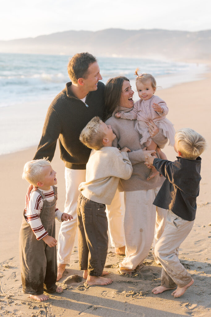 Parents laughing with their children during a playful sunset moment at Westward Beach.
