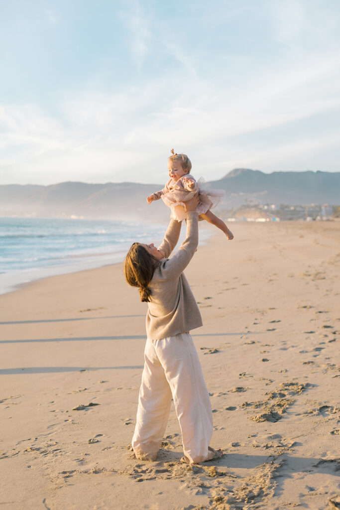 Family laughing and playing on beach together by Malibu photographer