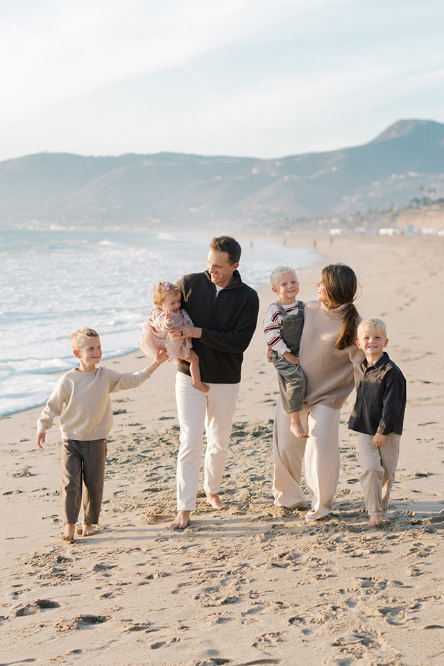 Family walking along the shoreline in warm golden light at Westward Beach in Malibu.