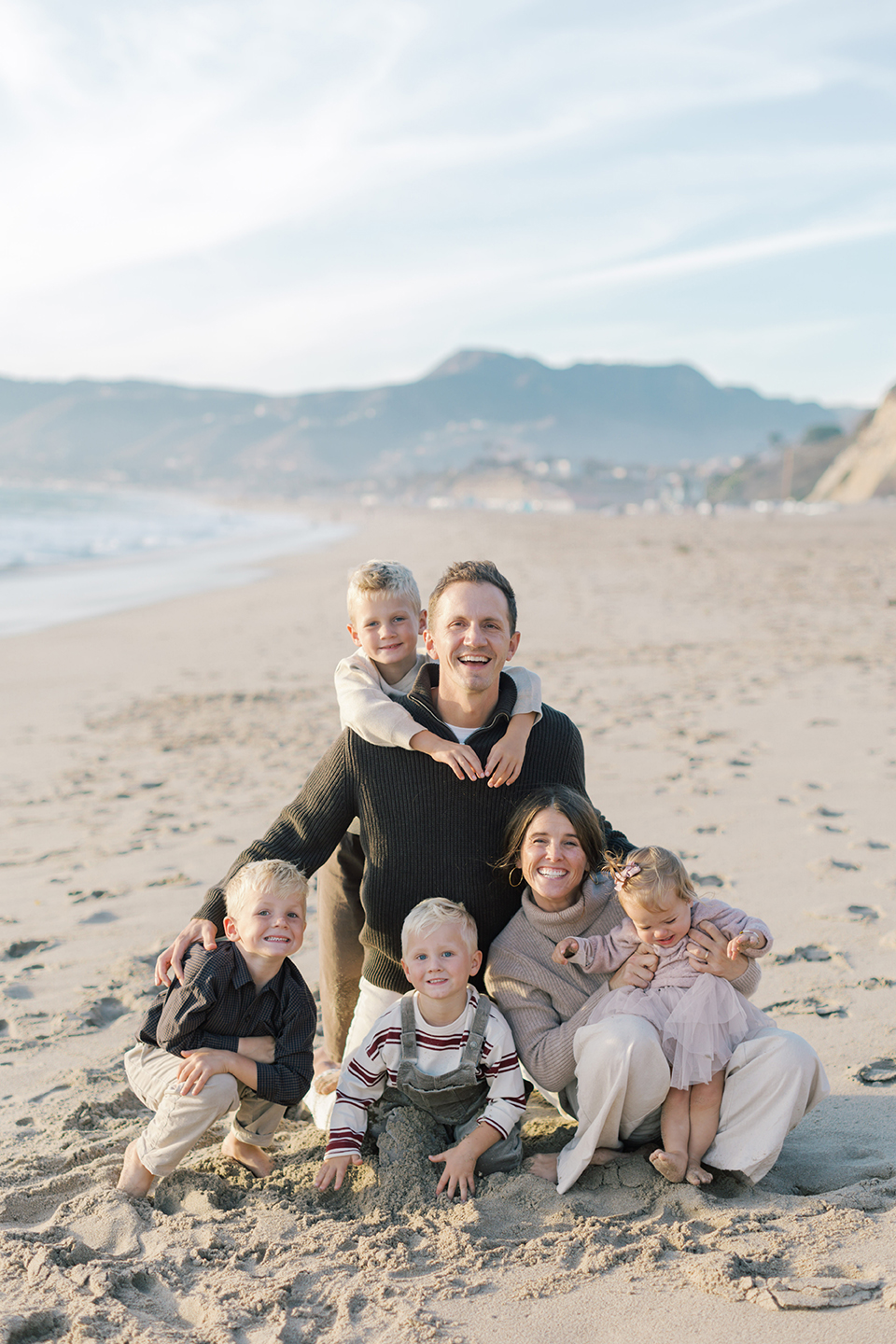 Parents sitting with their children in the sand during a lifestyle family session in Malibu.