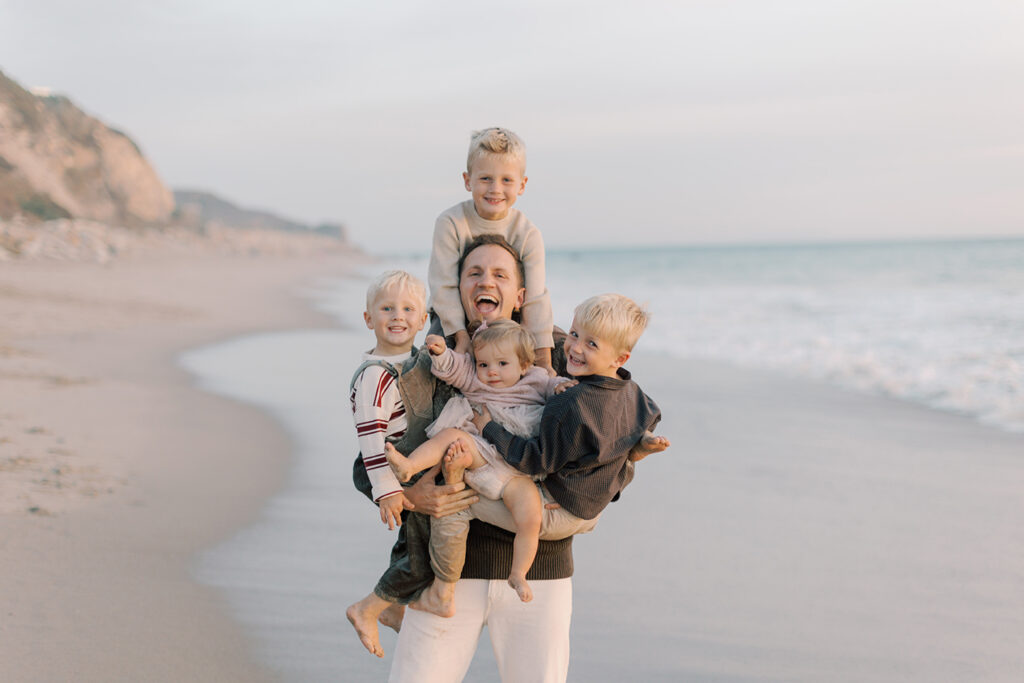 Candid Malibu family photo of dad holding four children and laughing by Malibu photographer.