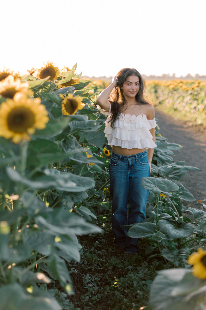 Full-length senior photo walking through a sunflower field near Thousand Oaks California at sunset