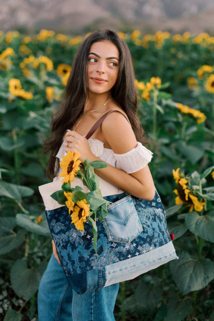 Senior portrait holding sunflowers with denim tote bag near Thousand Oaks photographed by a Calabasas senior photographer