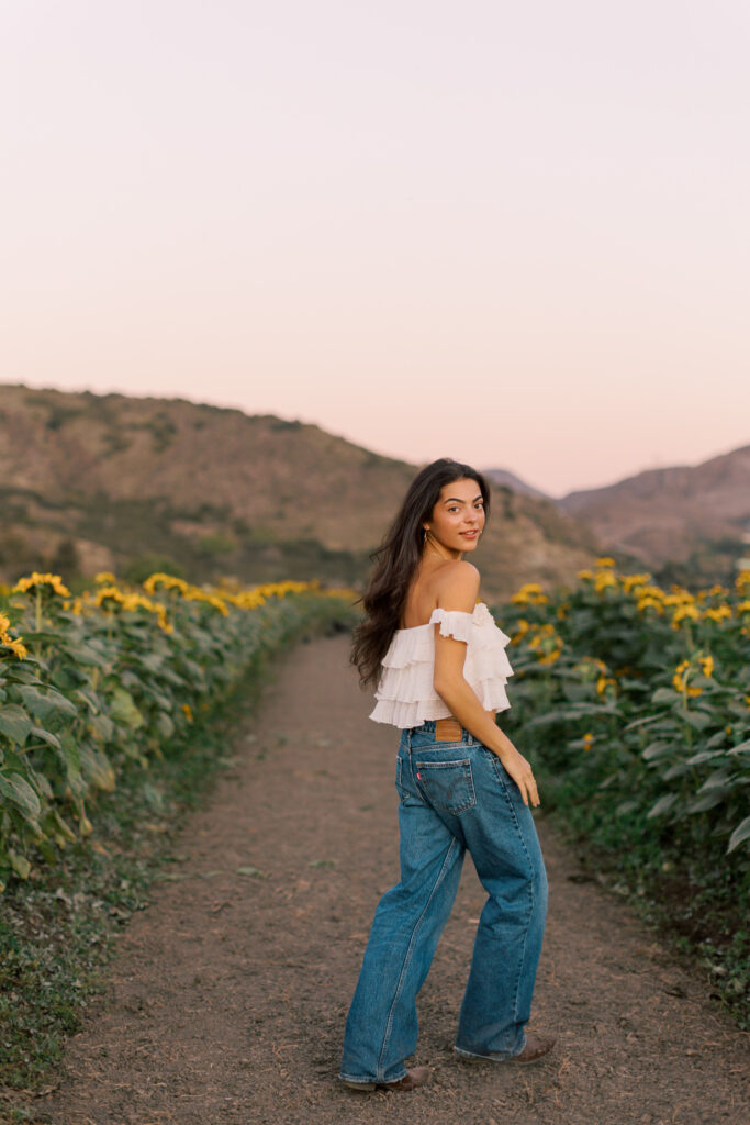 Senior walking down path in sunflower field by Westlake senior photographer