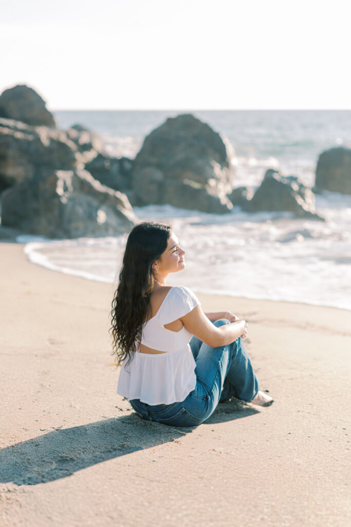 high school senior sitting on the sand at Malibu beach during sunset, natural posing senior photos Point Dume Southern California photographer
