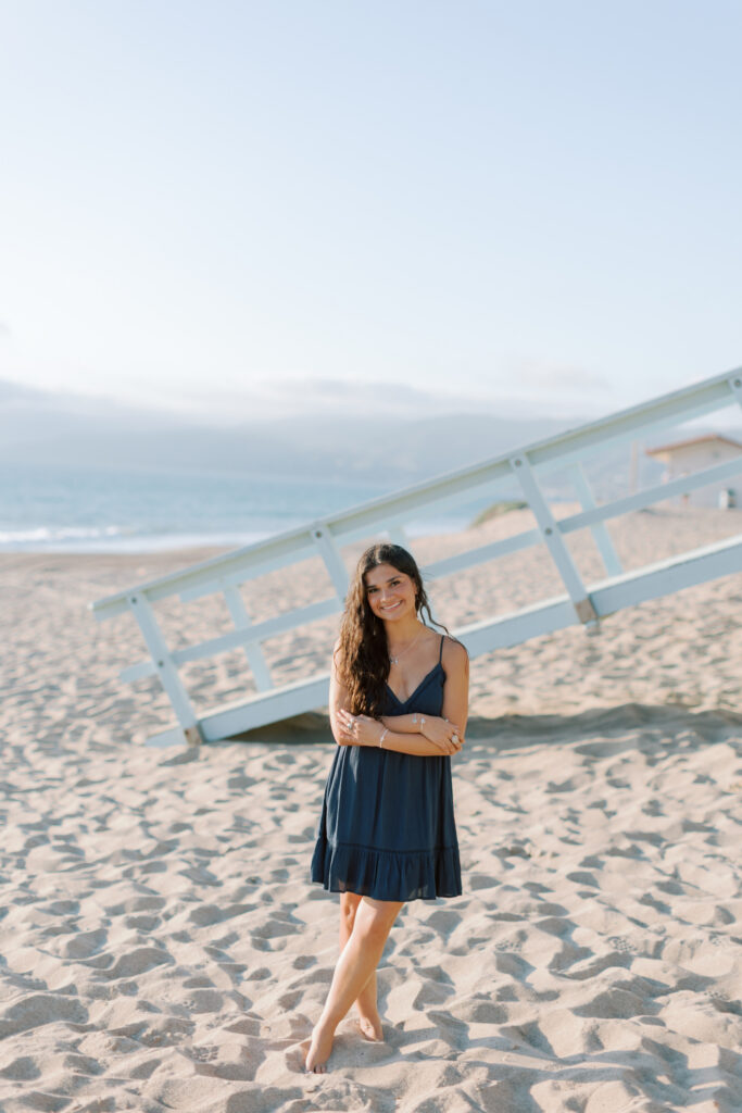 high school senior standing in sand near lifeguard tower at Westward Beach Malibu, full body portrait in navy dress, Thousand Oaks senior photographer