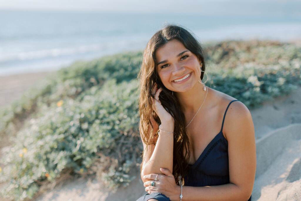 close up portrait of high school senior in navy dress at Westward Beach Malibu with soft natural light and ocean background