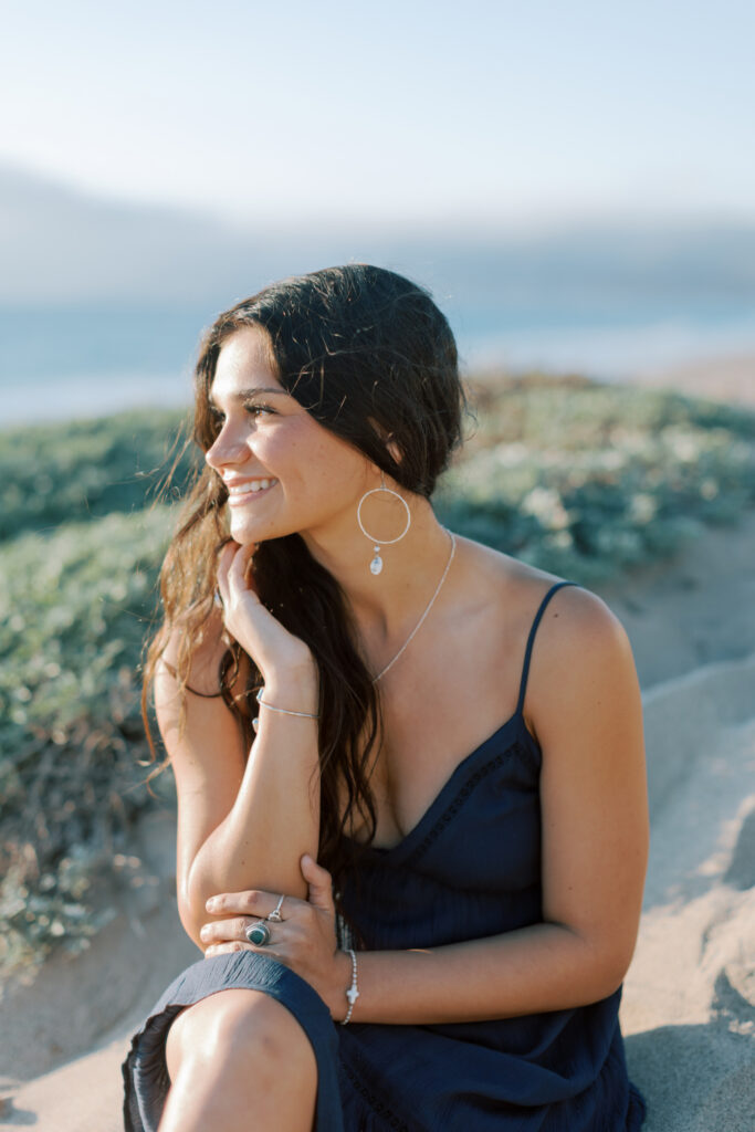 profile portrait of high school senior sitting in sand at Westward Beach Malibu with sunlight on face, candid beach senior photos Southern California