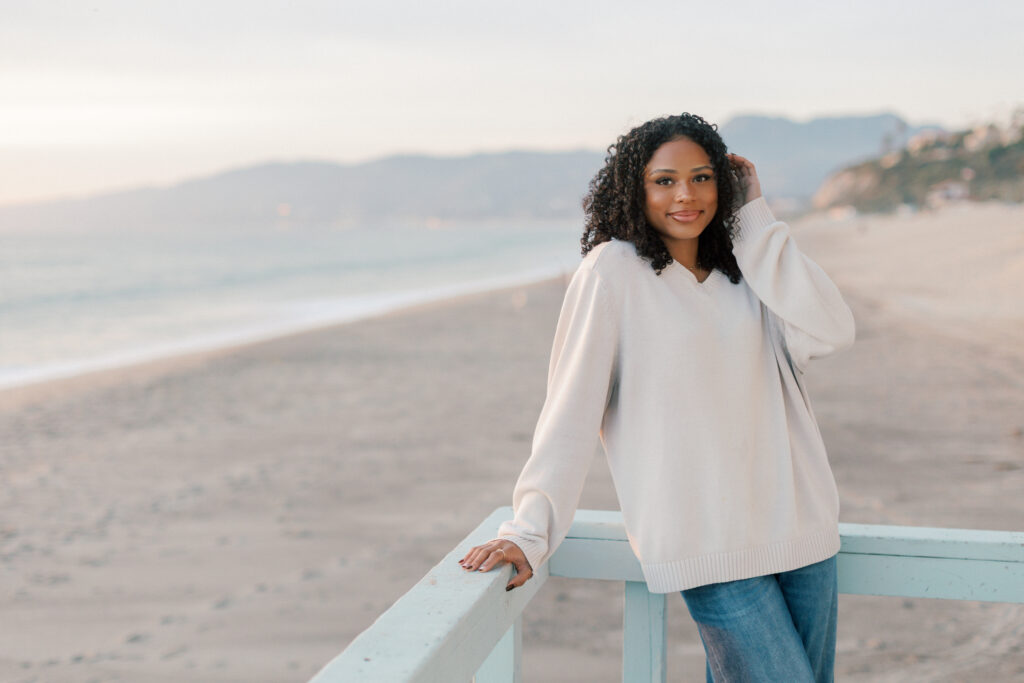 Oaks Christian senior photos at Point Dume Malibu leaning on a lifeguard stand with ocean and coastline in the background