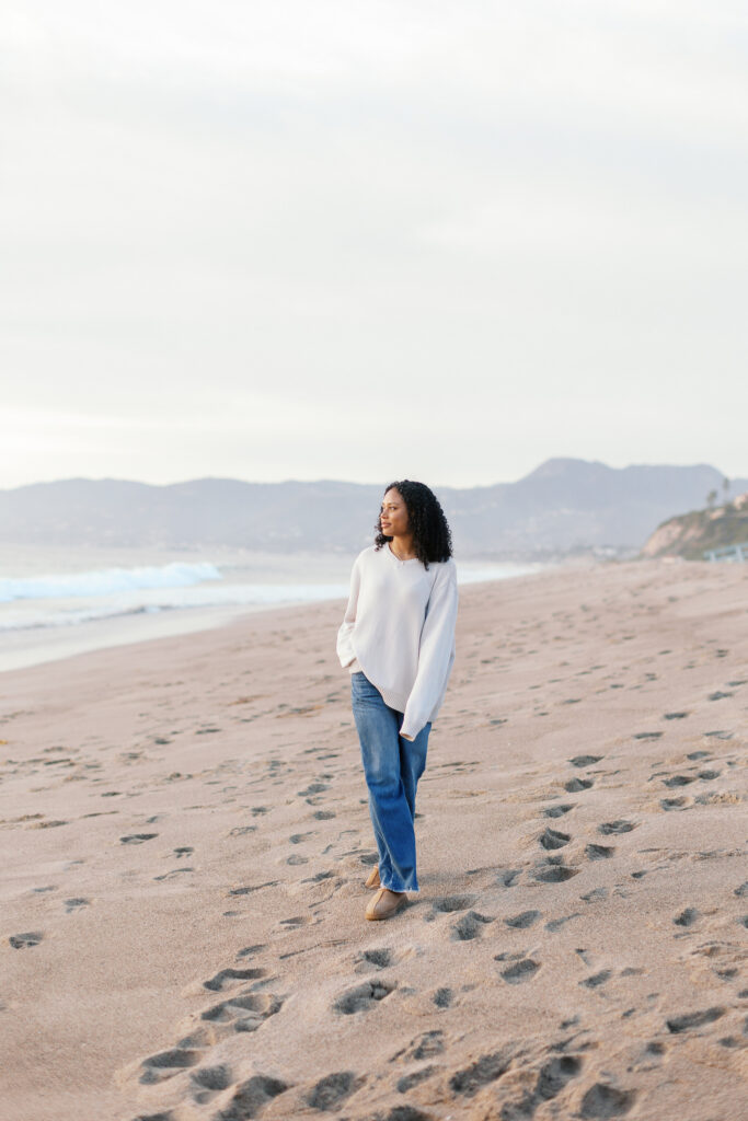 Southern California senior photos of Oaks Christian senior walking along Malibu beach at sunset