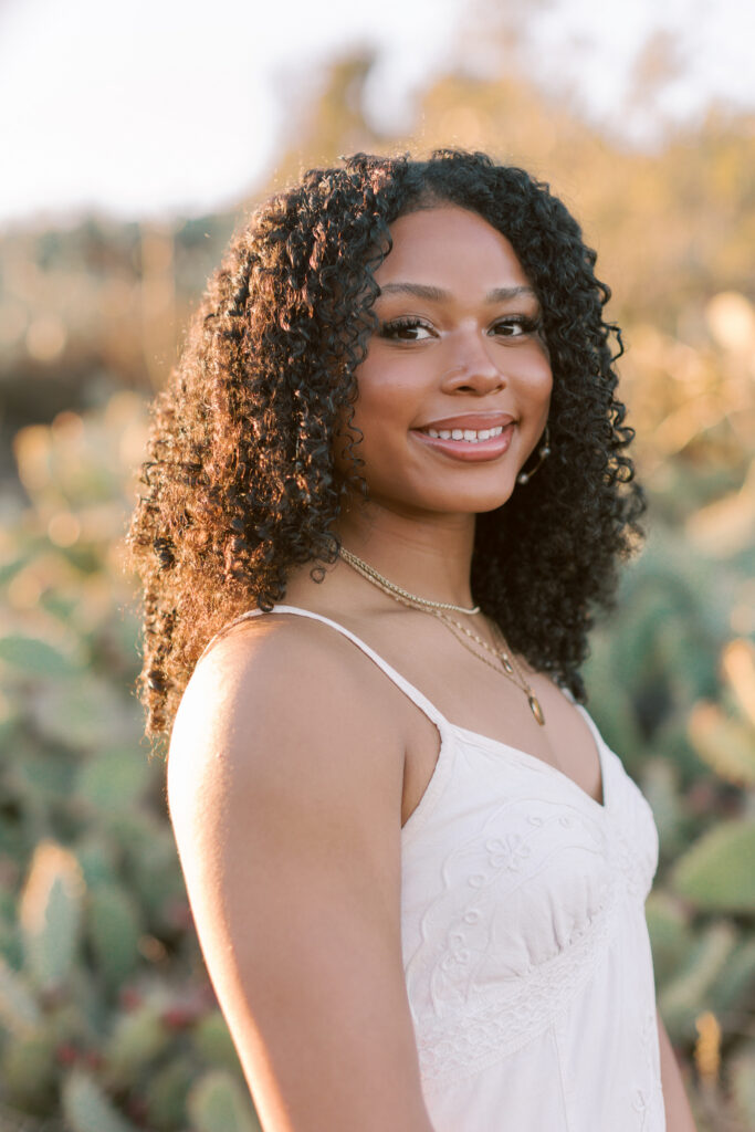Close-up portrait of a Thousand Oaks High School senior with curly hair in a white dress at sunset in the Santa Monica Mountains