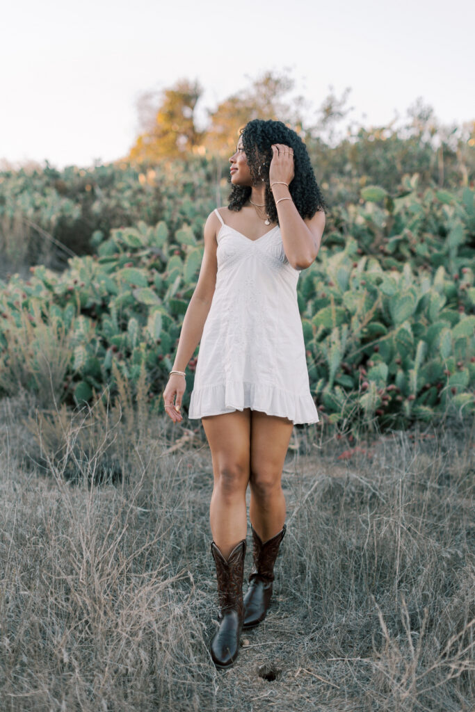 Thousand Oaks High School senior walking through a cactus field in the Santa Monica Mountains wearing a white dress and boots