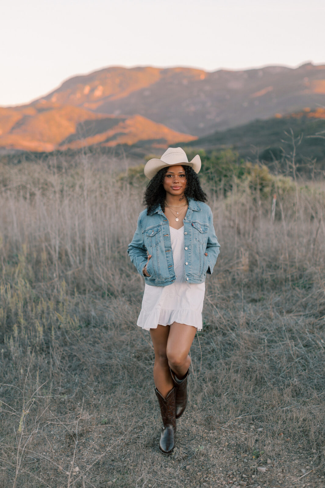 Thousand Oaks senior walking through a field in the Santa Monica Mountains with warm sunset light on the hills behind her